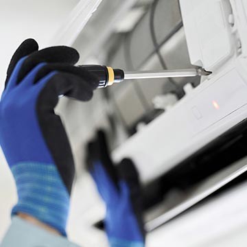 Techniker repariert Klimaanlage mit Schraubendreher