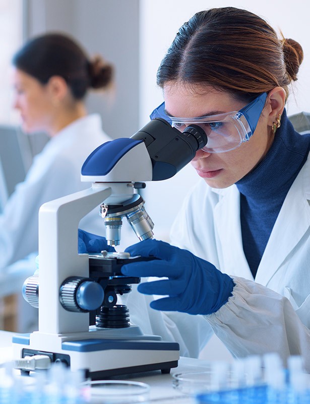 Wissenschaftlerin untersucht Probe unter Mikroskop im Labor